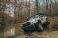 Tan 3rd Gen Tacoma flexing out suspension in a puddle