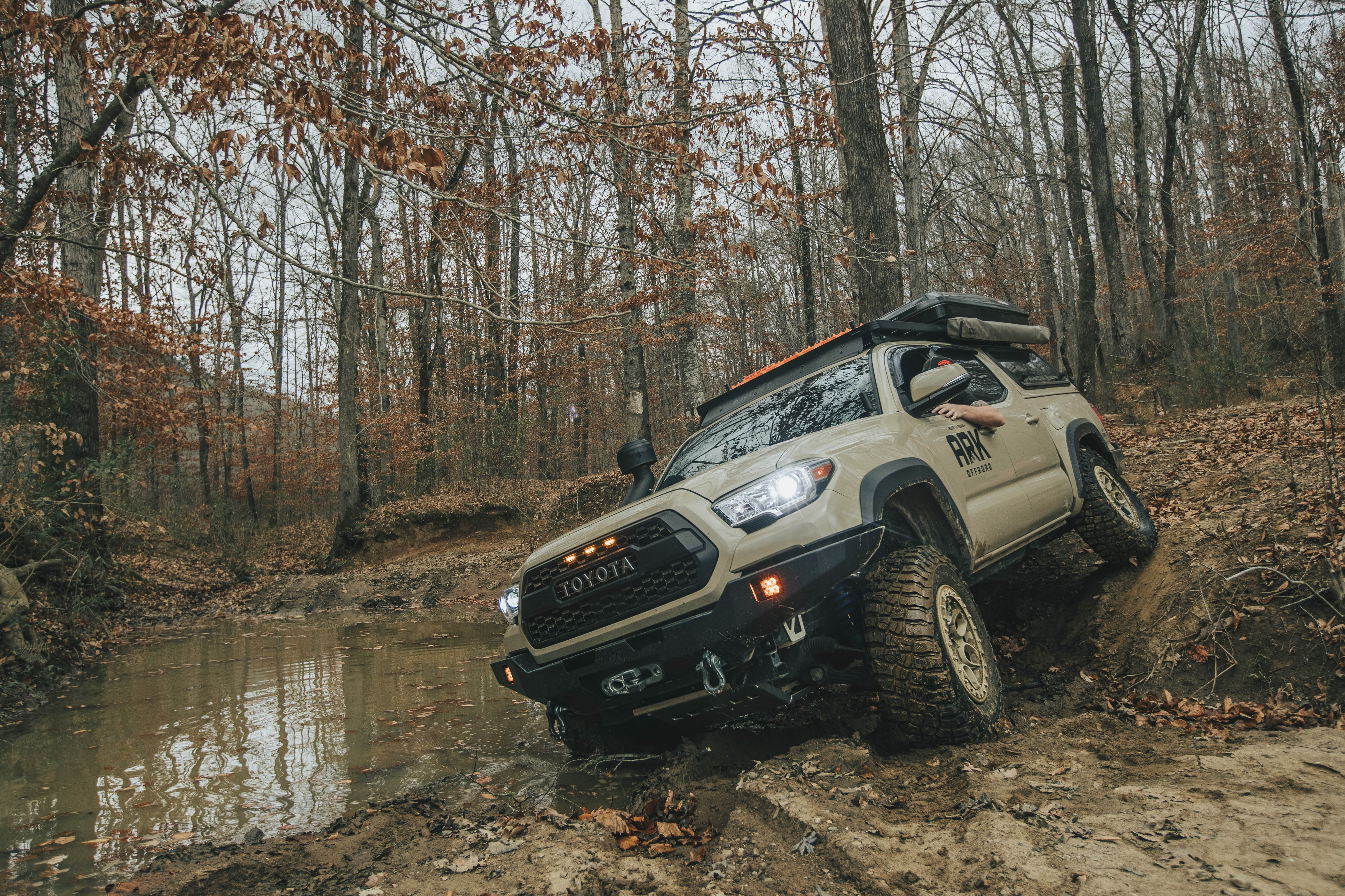 Tan 3rd Gen Tacoma flexing out suspension in a puddle